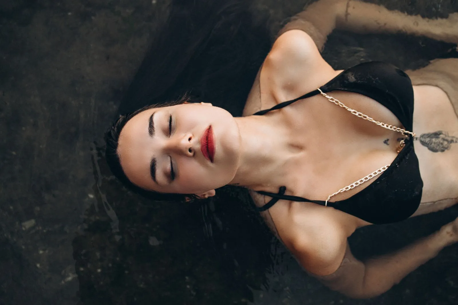 Portrait of a serene woman in a bikini floating in water with eyes closed.